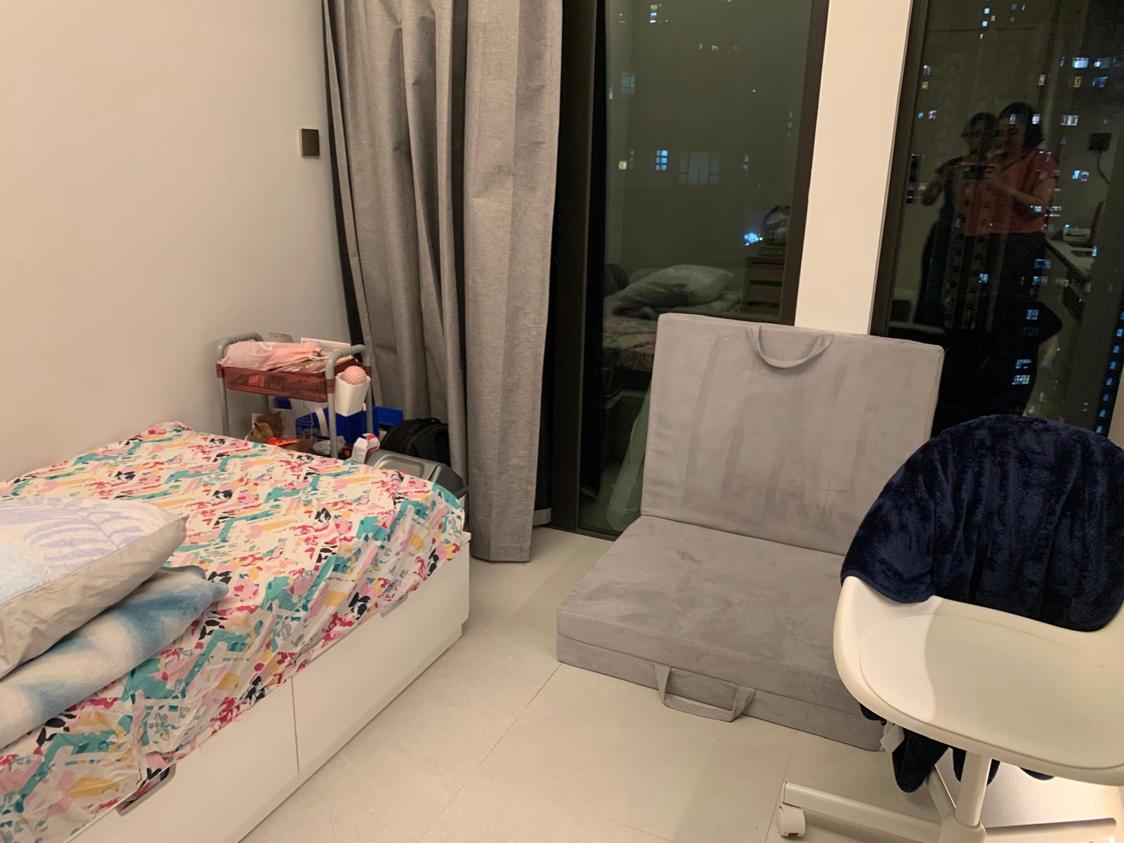 A compact rental bedroom at night showing overlapping sleeping and seating arrangements in a lived-in client apartment