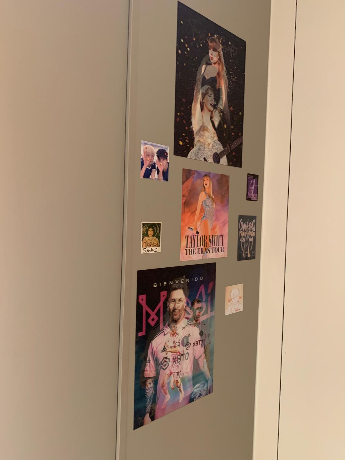 A personalised wall in a client's rental bedroom showing layered posters and prints that reflect individual identity within a compact living space